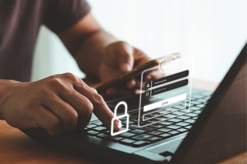 Someone looking at a credit card and typing on a laptop.