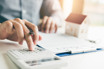 Mans hands typing on calculator budgeting mortgage expenses