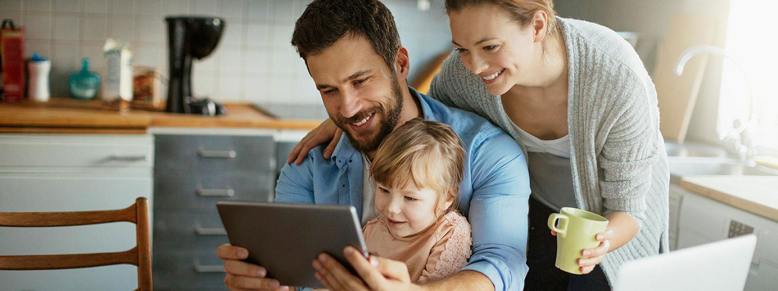 Young family looking at tablet in kitchen