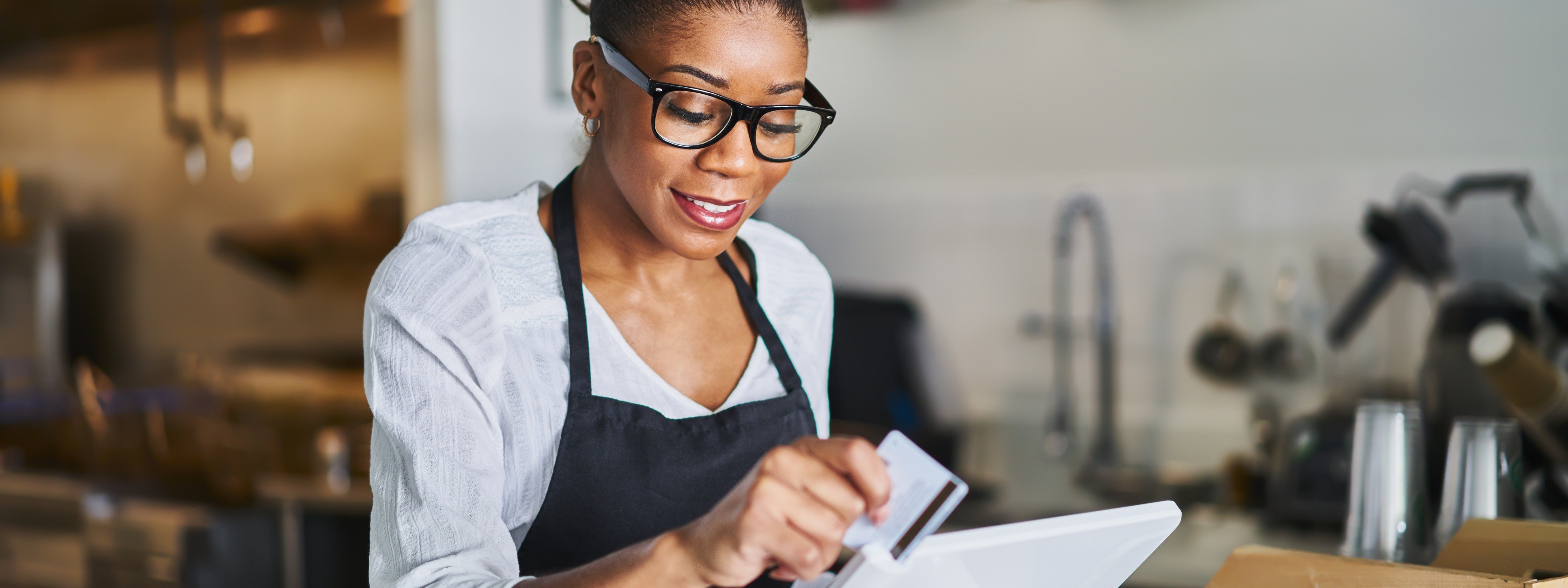 A woman hold a credit card getting ready to swipe it for a transaction