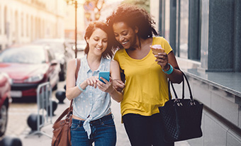 Two young women transferring money with smartphones