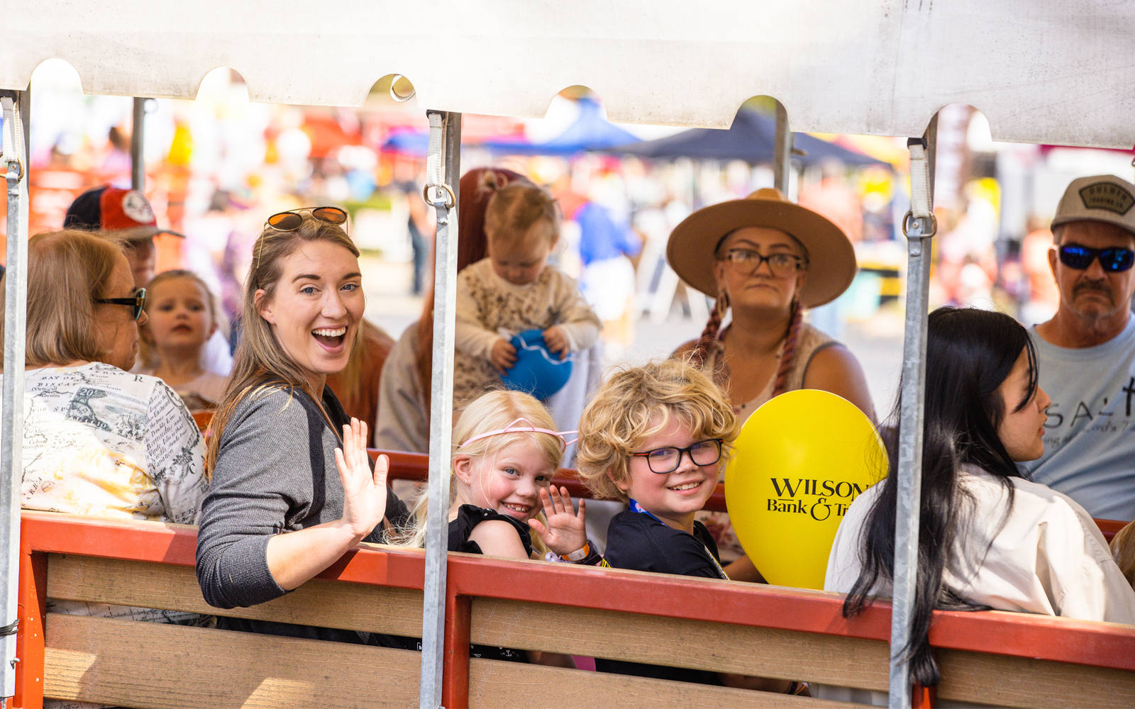 A mom, son, and daughter sitting on transportation at Oktoberfest and smiling.