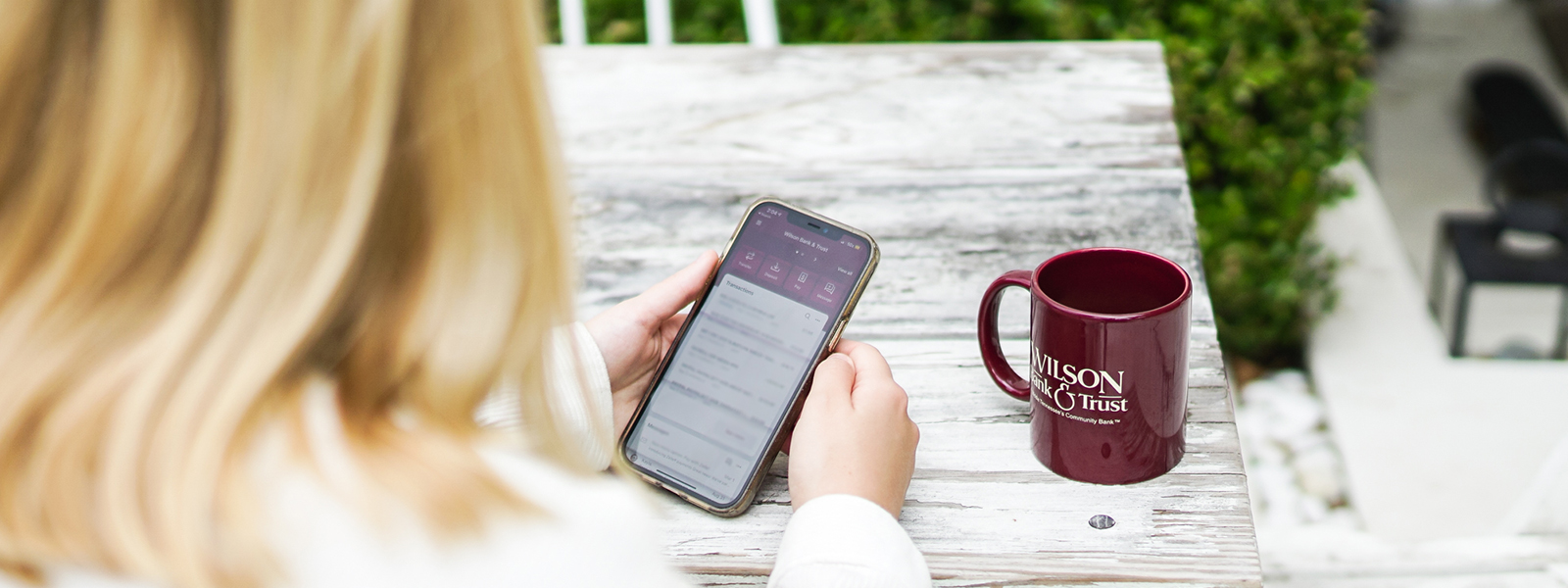 A woman is on her phone while drinking coffee