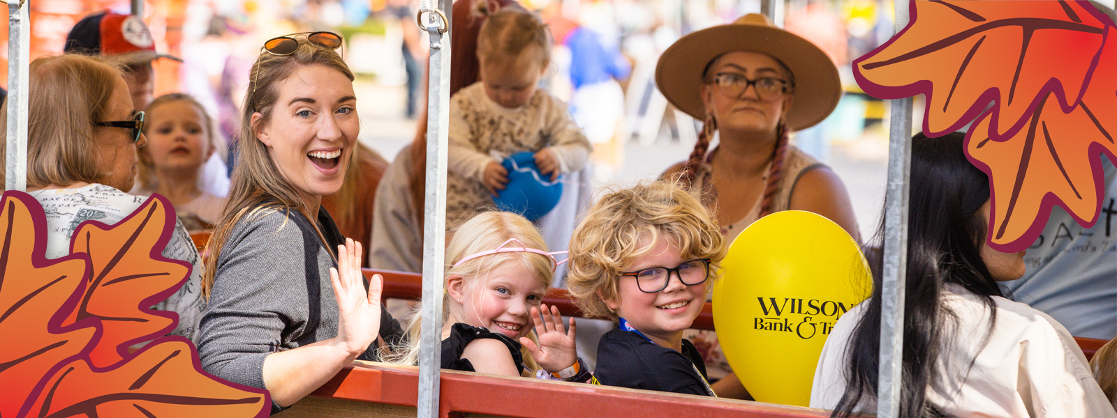 A mom, son, and daughter sitting on transportation at Oktoberfest and smiling.