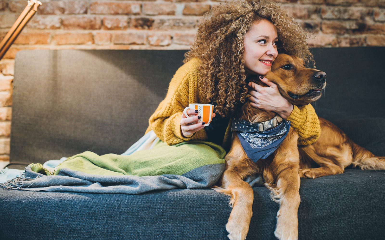Woman cuddling dog on couch in living room