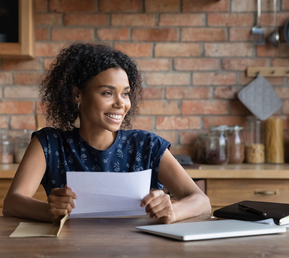 A woman sitting down and smiling while holding a paper.